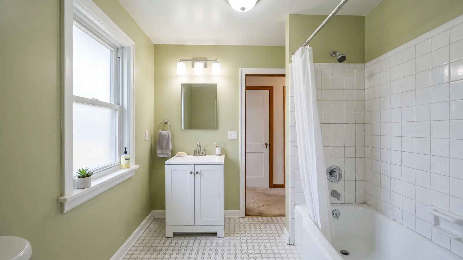 Small budget bathroom refresh with a new white vanity, mirror, light fixture and reglazed tub