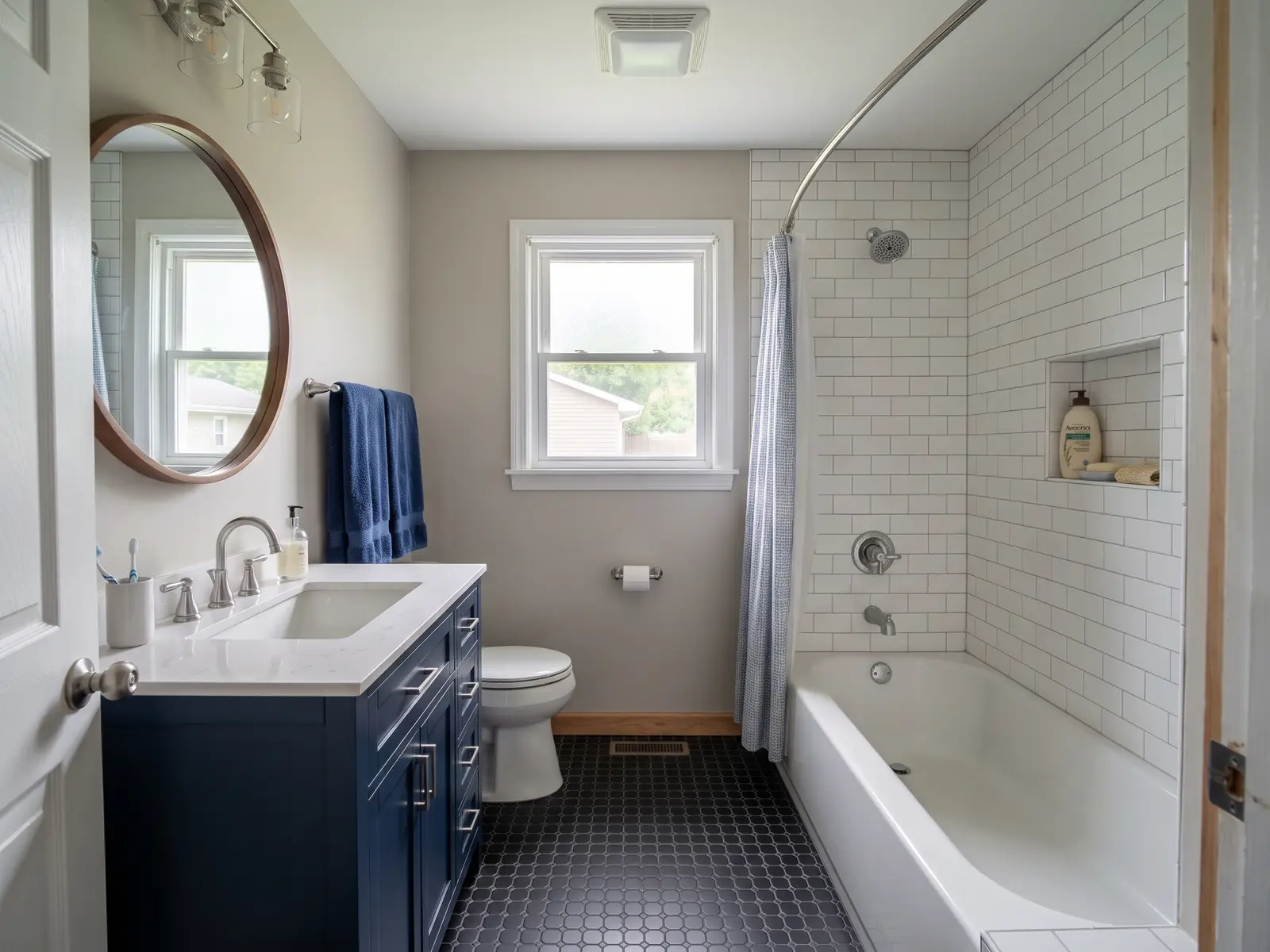 Fully remodeled hall bathroom in a Fort Wayne ranch home with a new tub, white tile and navy vanity