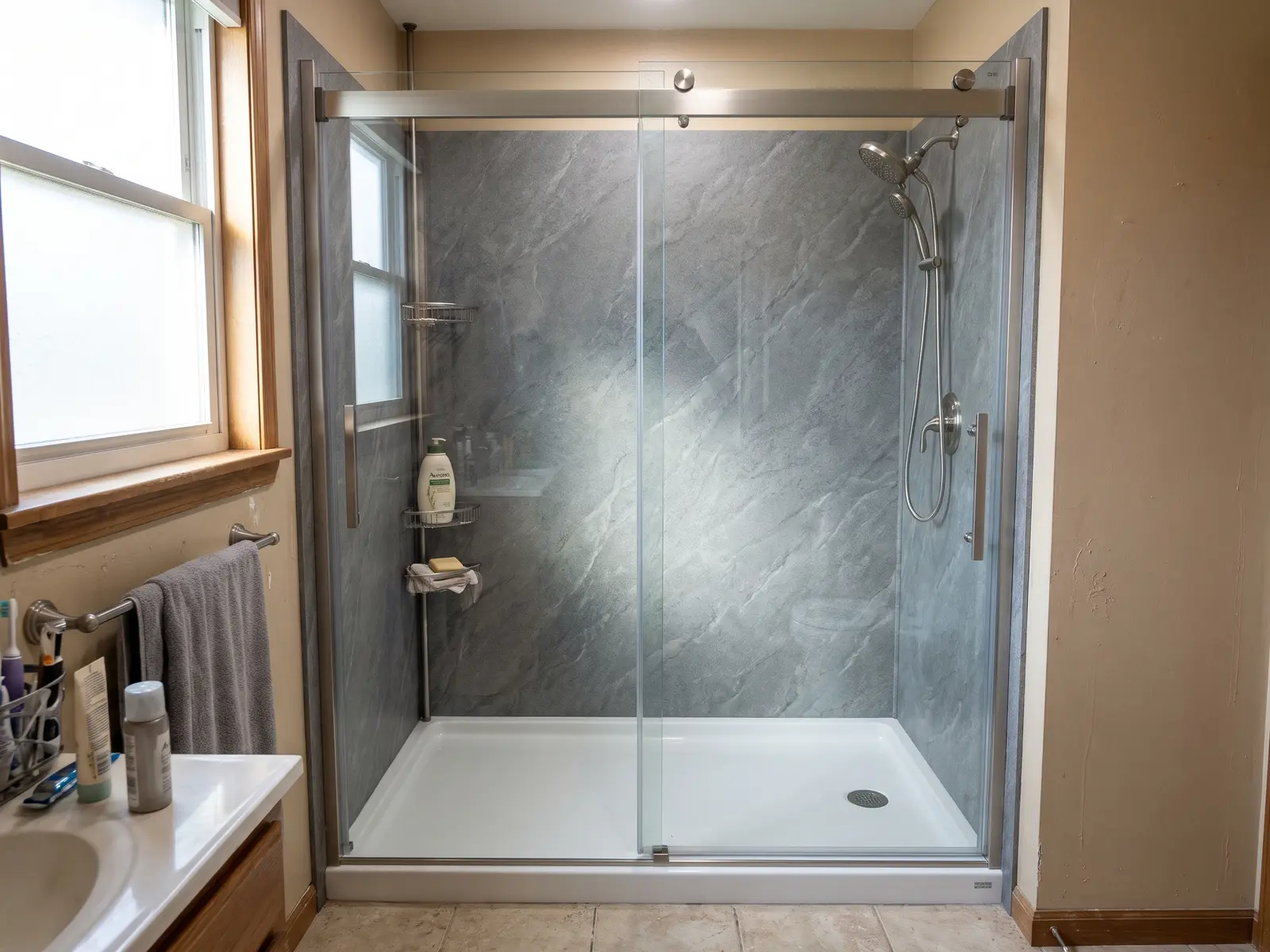 New replacement shower with gray stone-look solid-surface wall panels, white base and clear sliding glass door