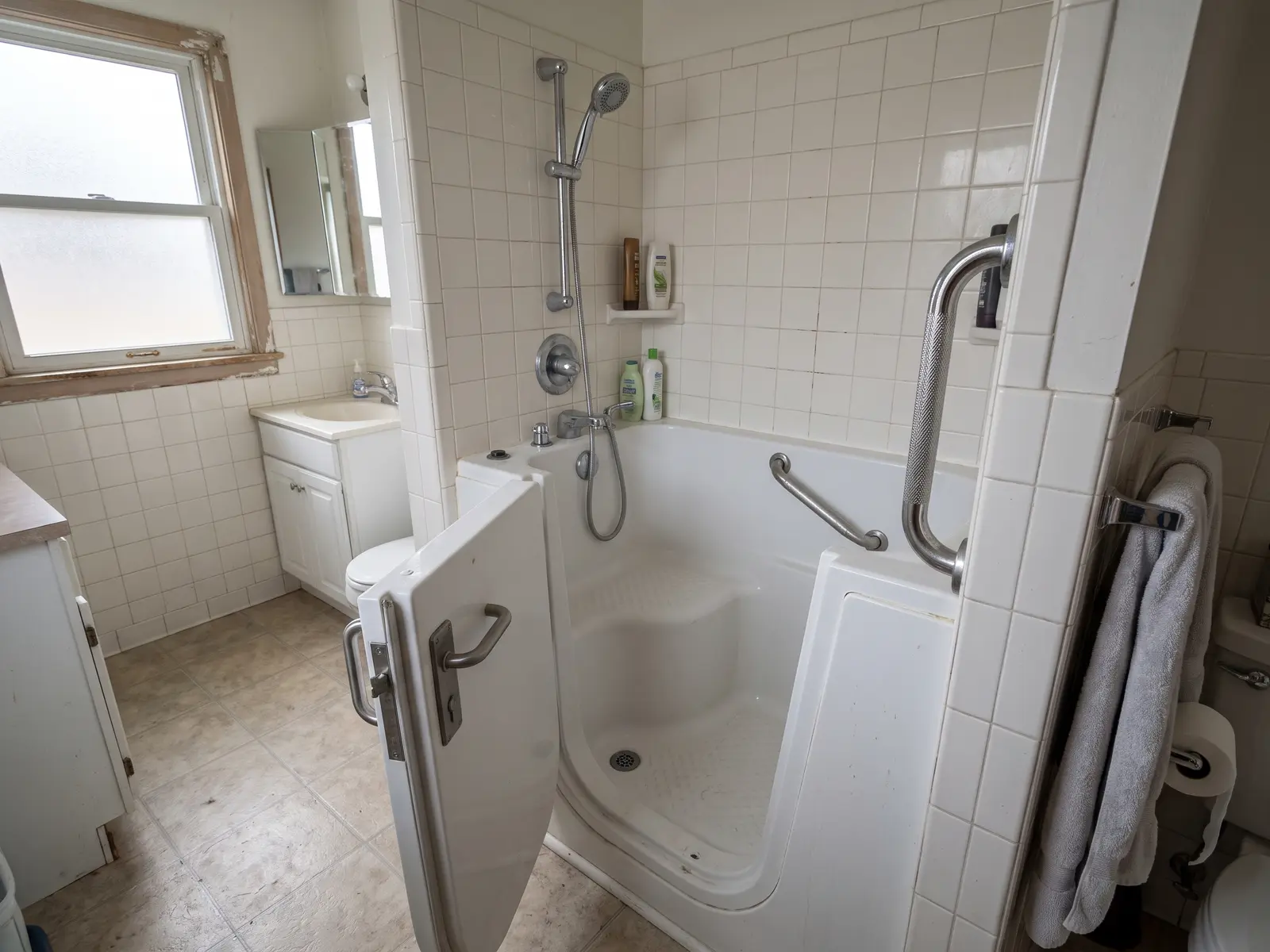Walk-in bathtub with a side door, built-in seat and grab bar in a Fort Wayne bathroom